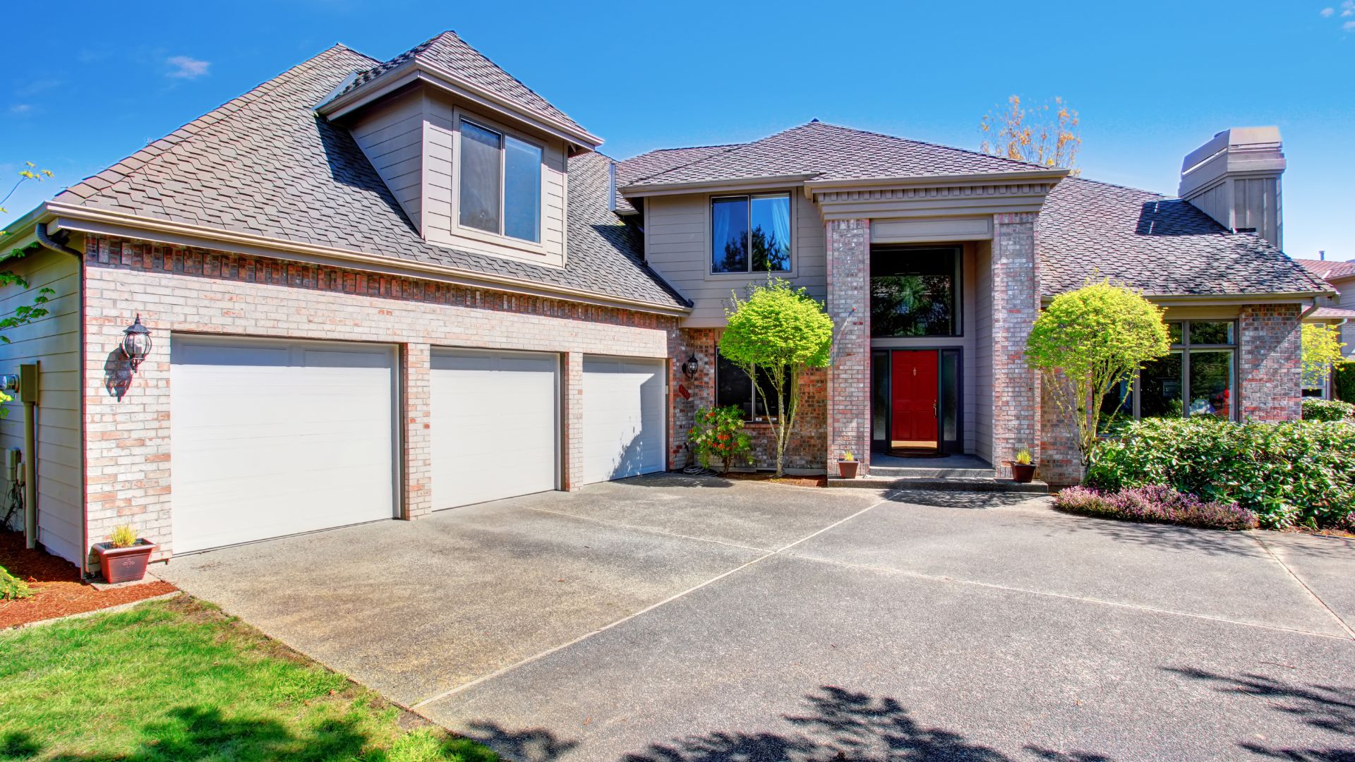 Luxury two-story brick house with three-car garage and manicured landscaping