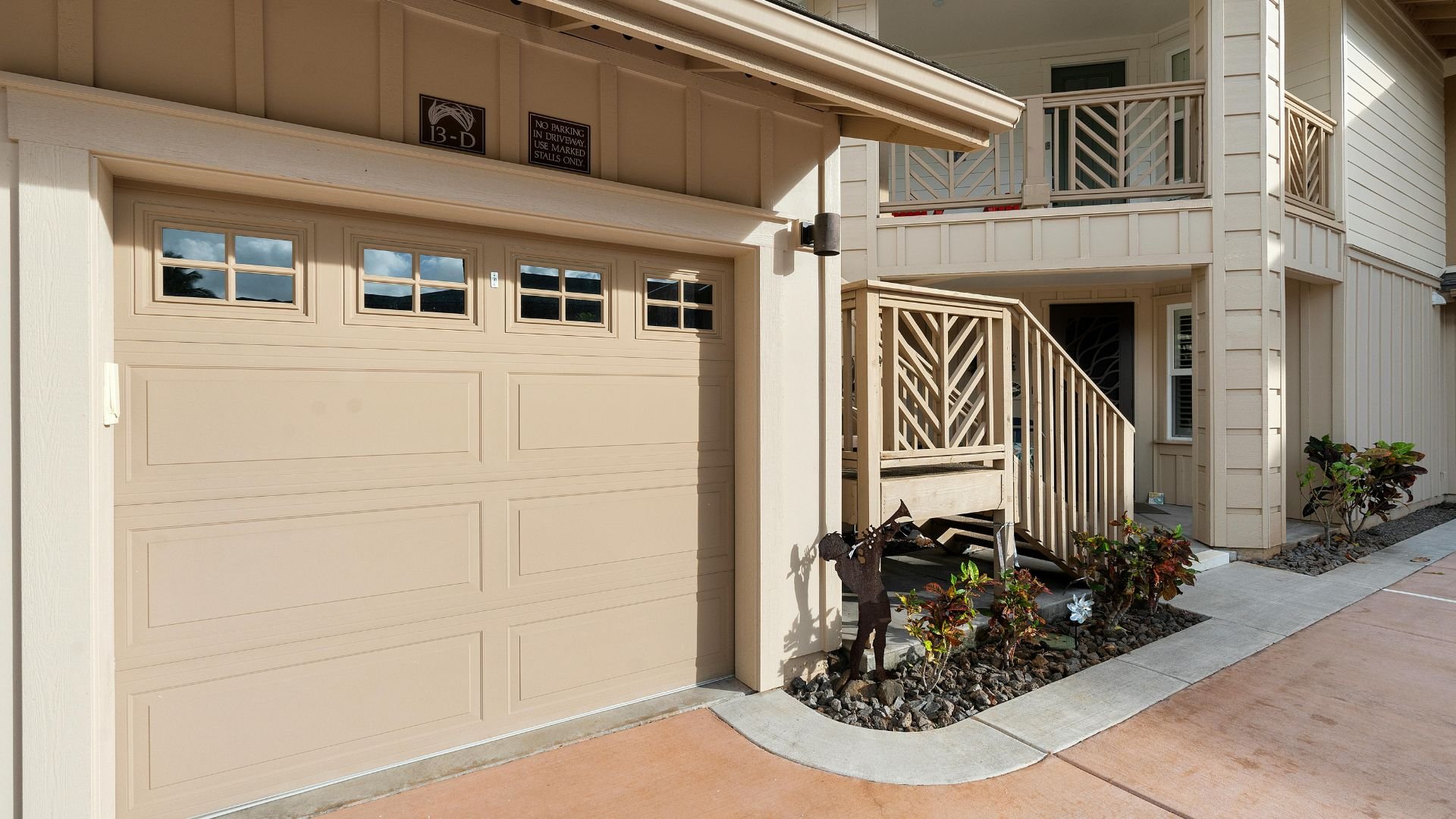 Beige garage with windows, decorative staircase, and small landscaped garden area